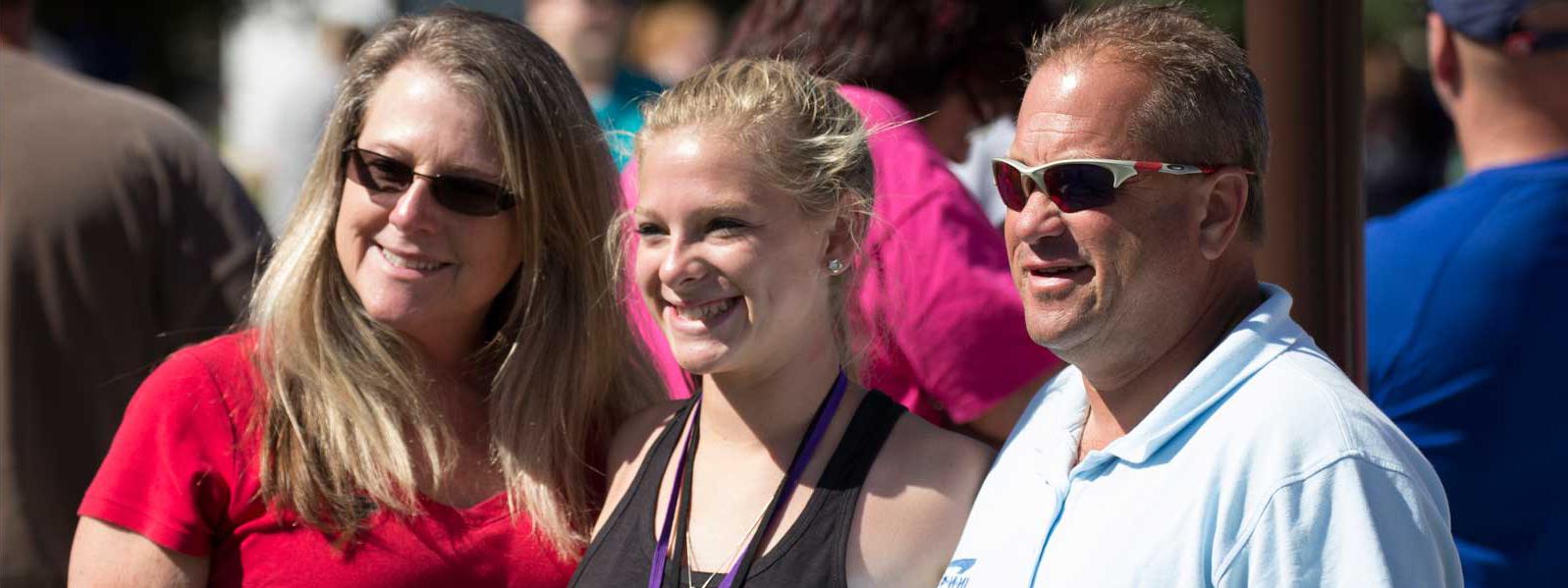 mom, dad, and student pose for picture on move-in day